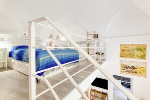 A bedroom with a bunk bed, a staircase, a bookshelf, and framed artwork on the wall.