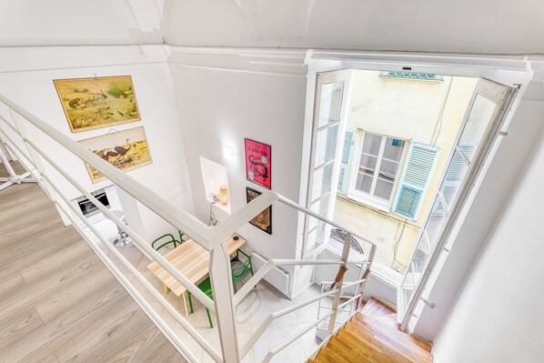 A staircase with a view of a dining area and artwork on the walls.