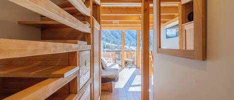 A wooden interior with built-in shelves, a bench, and a view of mountains through large windows.