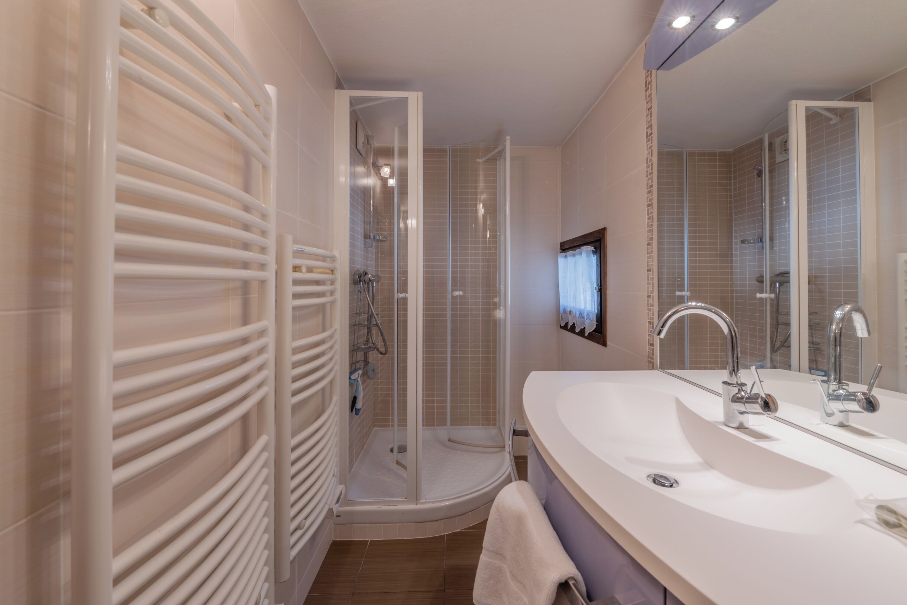A modern bathroom with a walk-in shower, a large vanity with a double sink, and a large mirror.