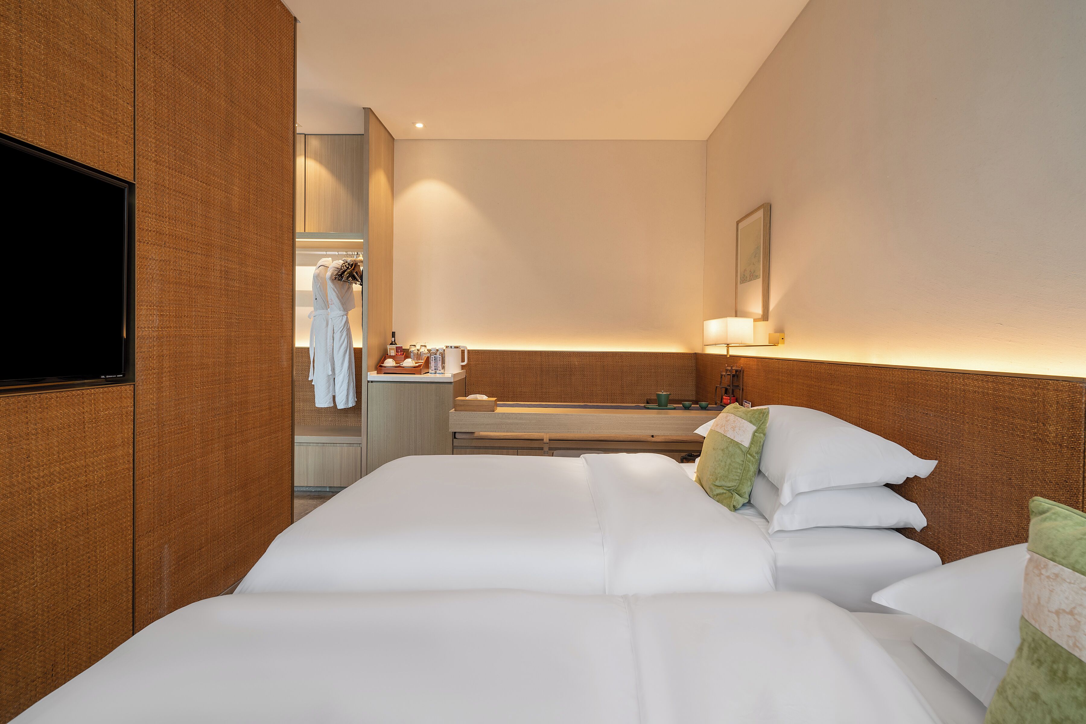 A hotel room with a large bed, a flat-screen TV, a bathroom with a mirror, and a small table with toiletries.