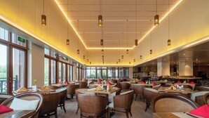 Un espaiós restaurant amb sostres alts, il·luminació penjant i grans finestres que ofereixen vistes a l'exterior.