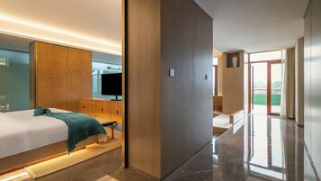 Une chambre d’hôtel moderne dotée d’un grand lit, d’une tête de lit en bois, d’un téléviseur à écran plat et offrant une vue sur l’extérieur grâce à une porte coulissante.