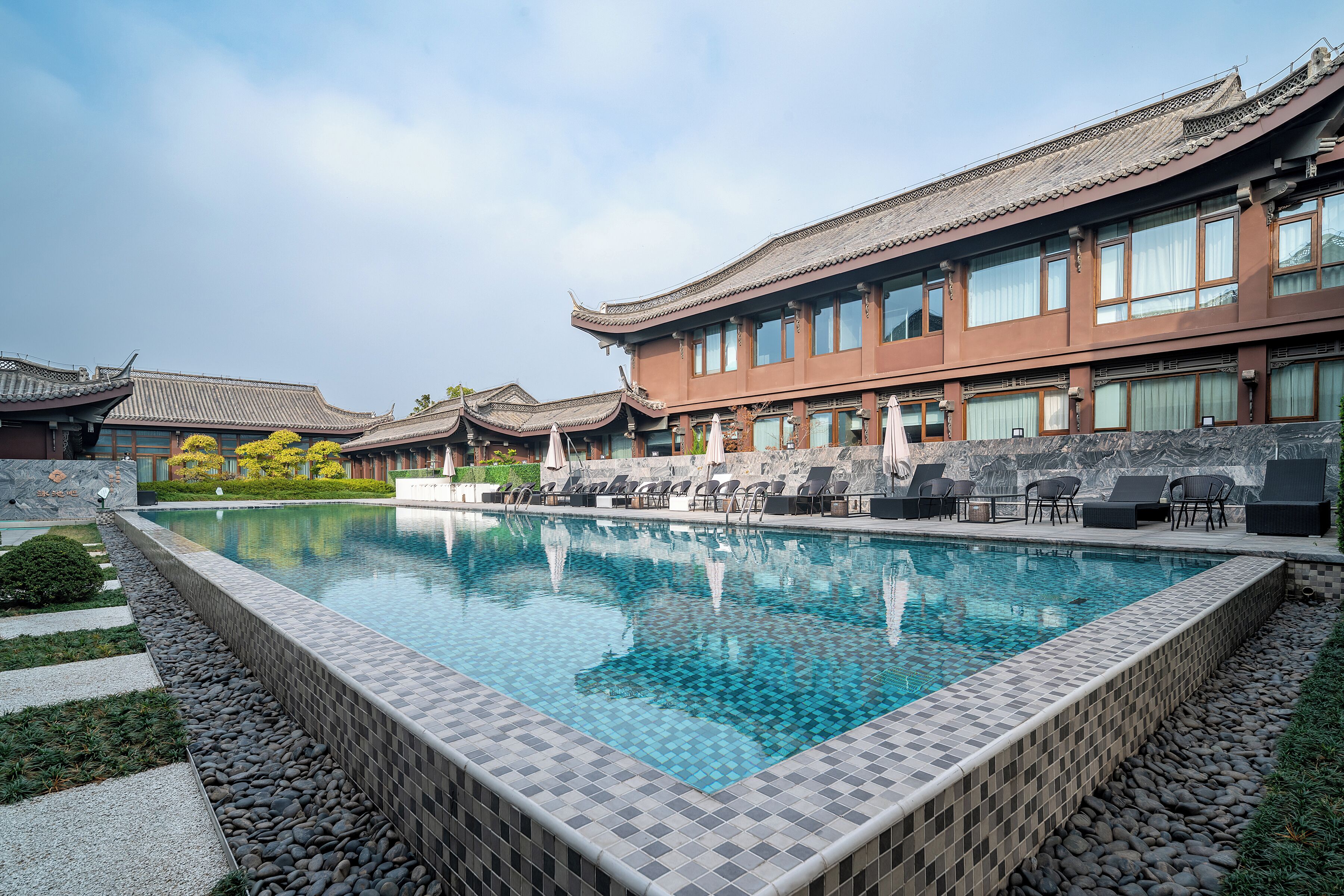 A traditional building with a swimming pool and lounge area.