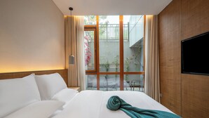 Habitació d'hotel amb un llit gran, un televisor penjat a la paret i vista cap a l'exterior.