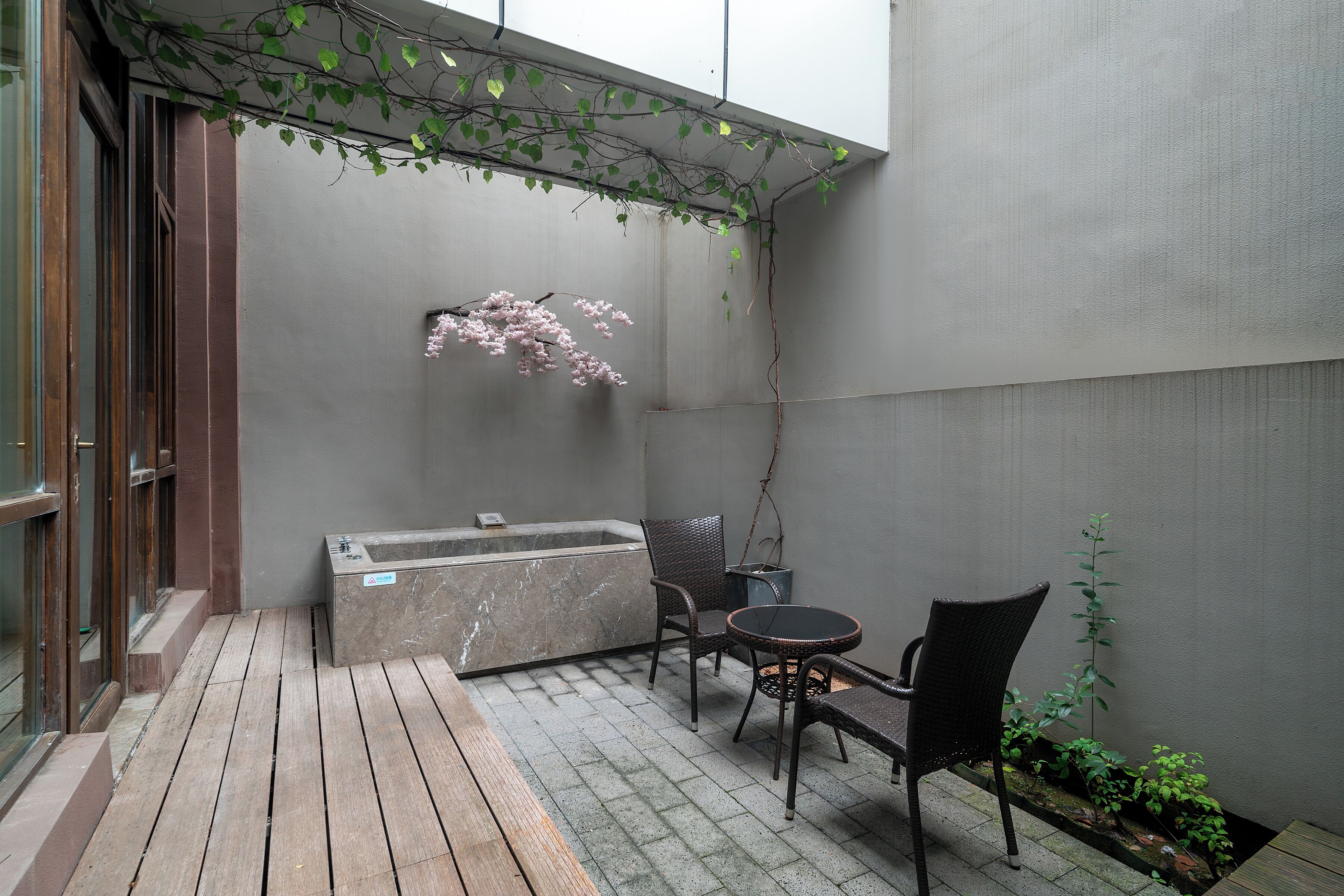 A small outdoor seating area with a table and chairs, a hot tub, and a wooden deck.