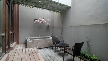 A small outdoor seating area with a table and chairs, a hot tub, and a wooden deck.