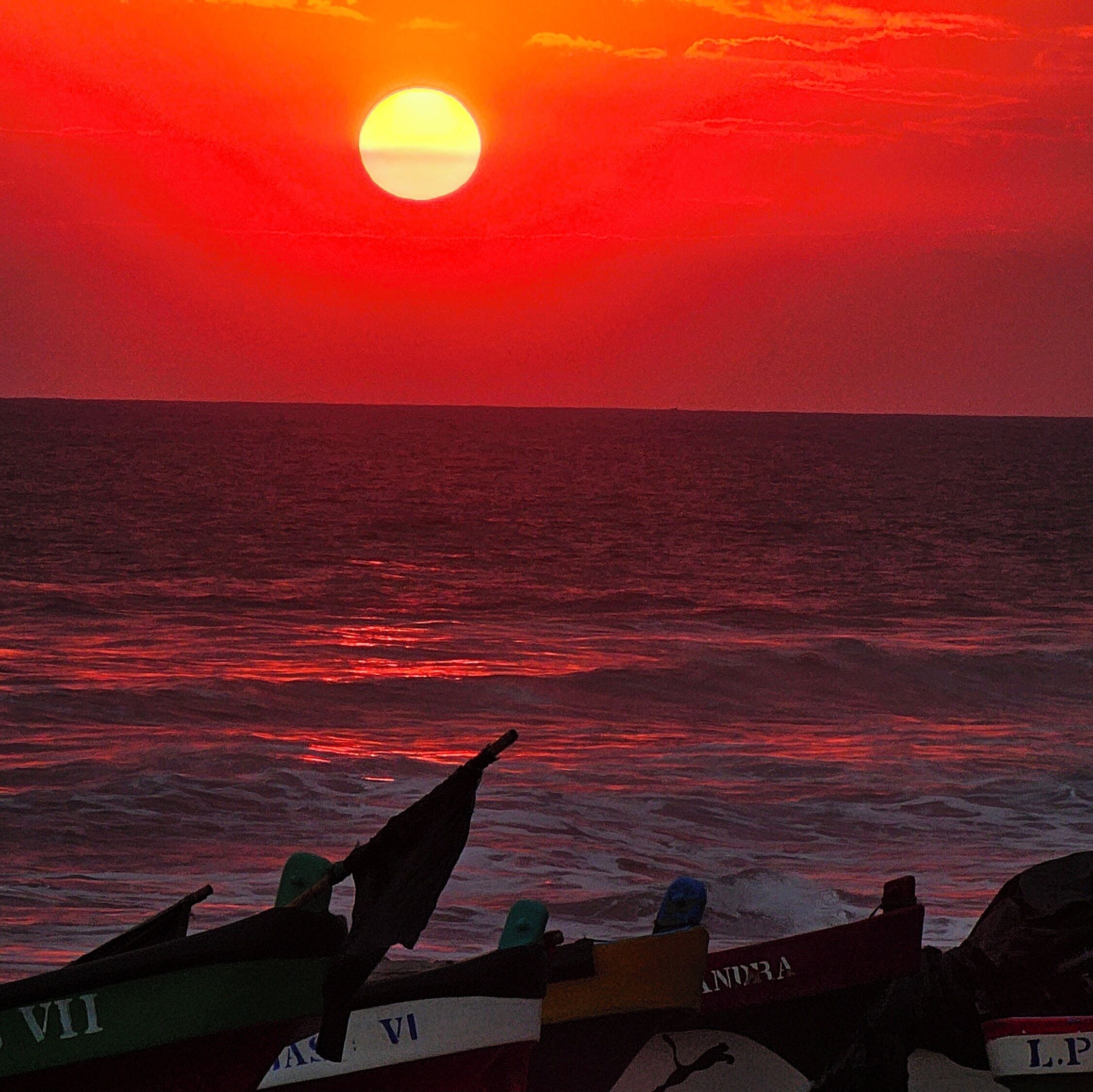 A sunset over the ocean with boats in the foreground.