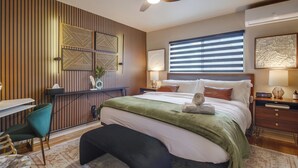 A modern bedroom with a bed, bedside tables, a desk, and a chair.