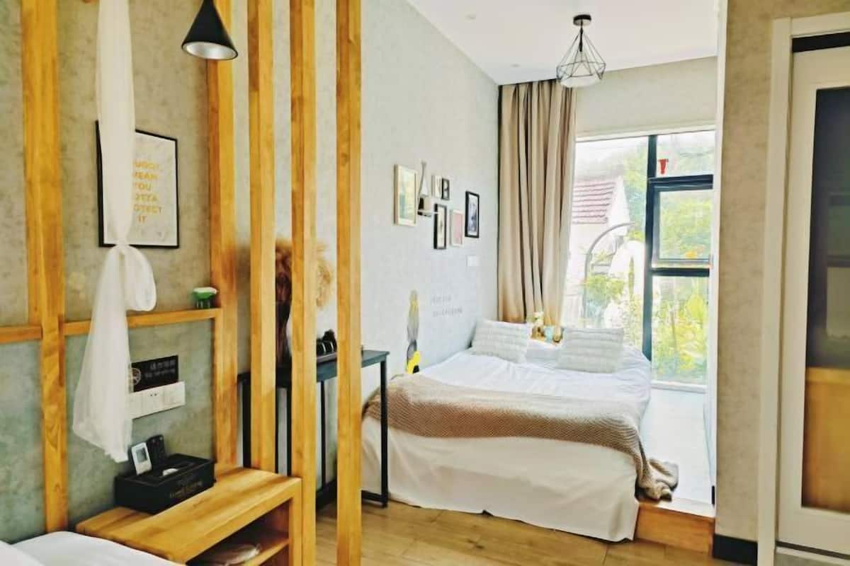 Un dormitorio con cama, escritorio, silla, lámpara colgante y ventana con cortinas.