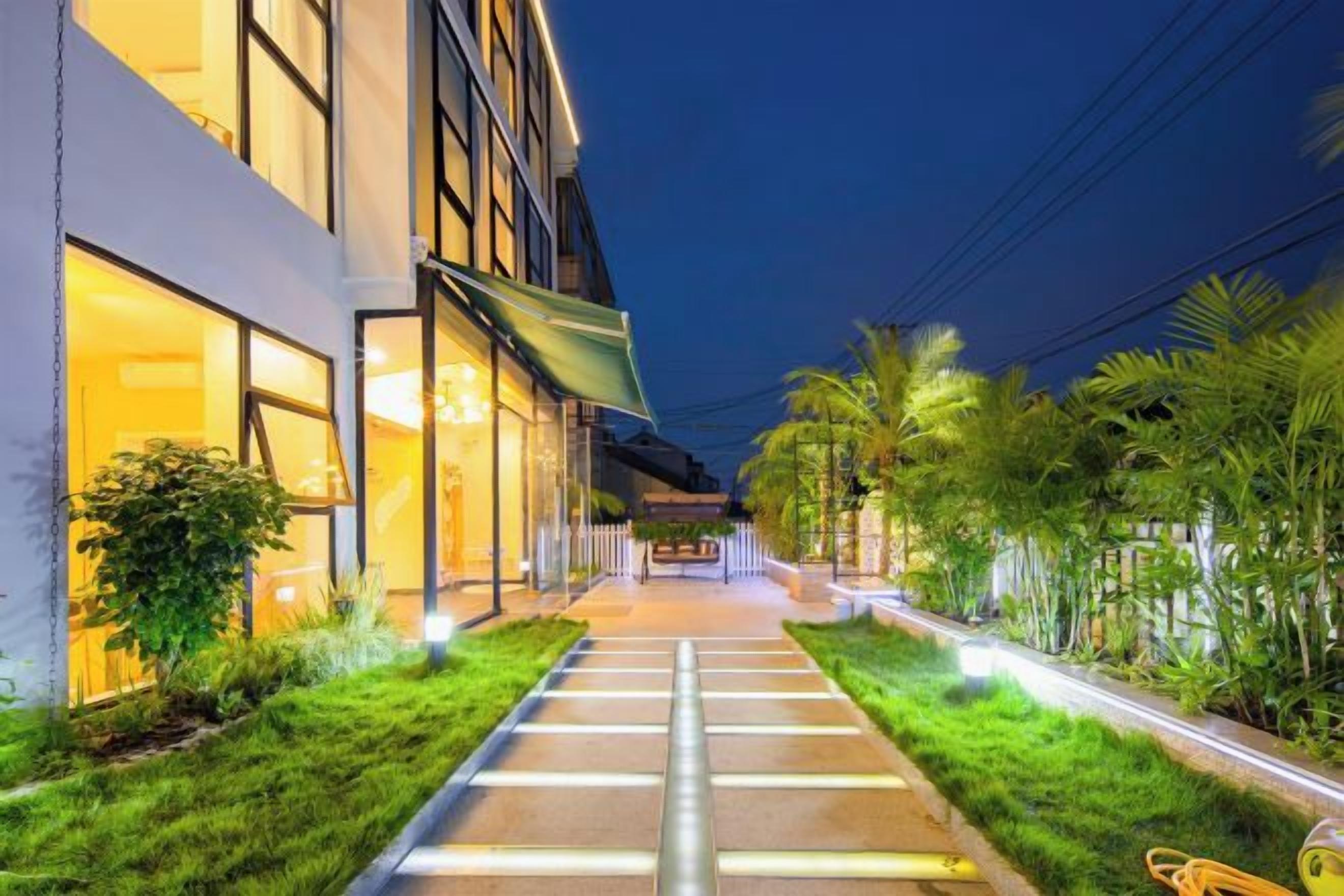 Un vialetto che conduce a un edificio con finestre illuminate e un giardino curato.