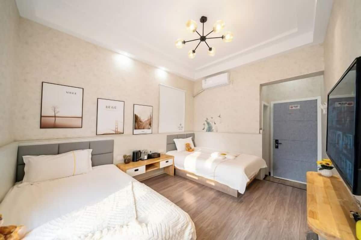 Habitación de hotel con dos camas, una mesita de noche de madera, un televisor y obras de arte en las paredes.