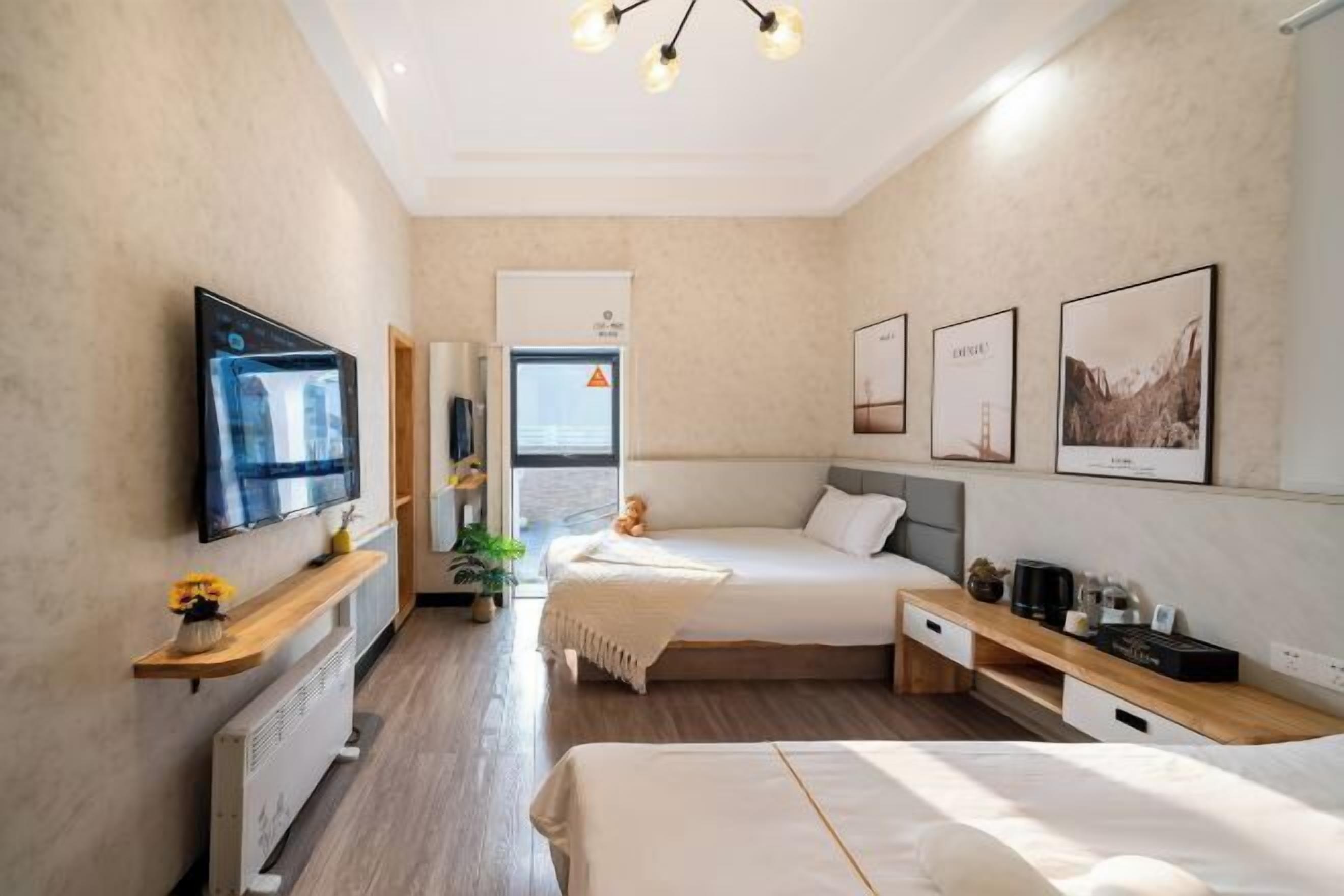 A modern hotel room with a bed, bedside tables, a TV, and artwork on the walls.