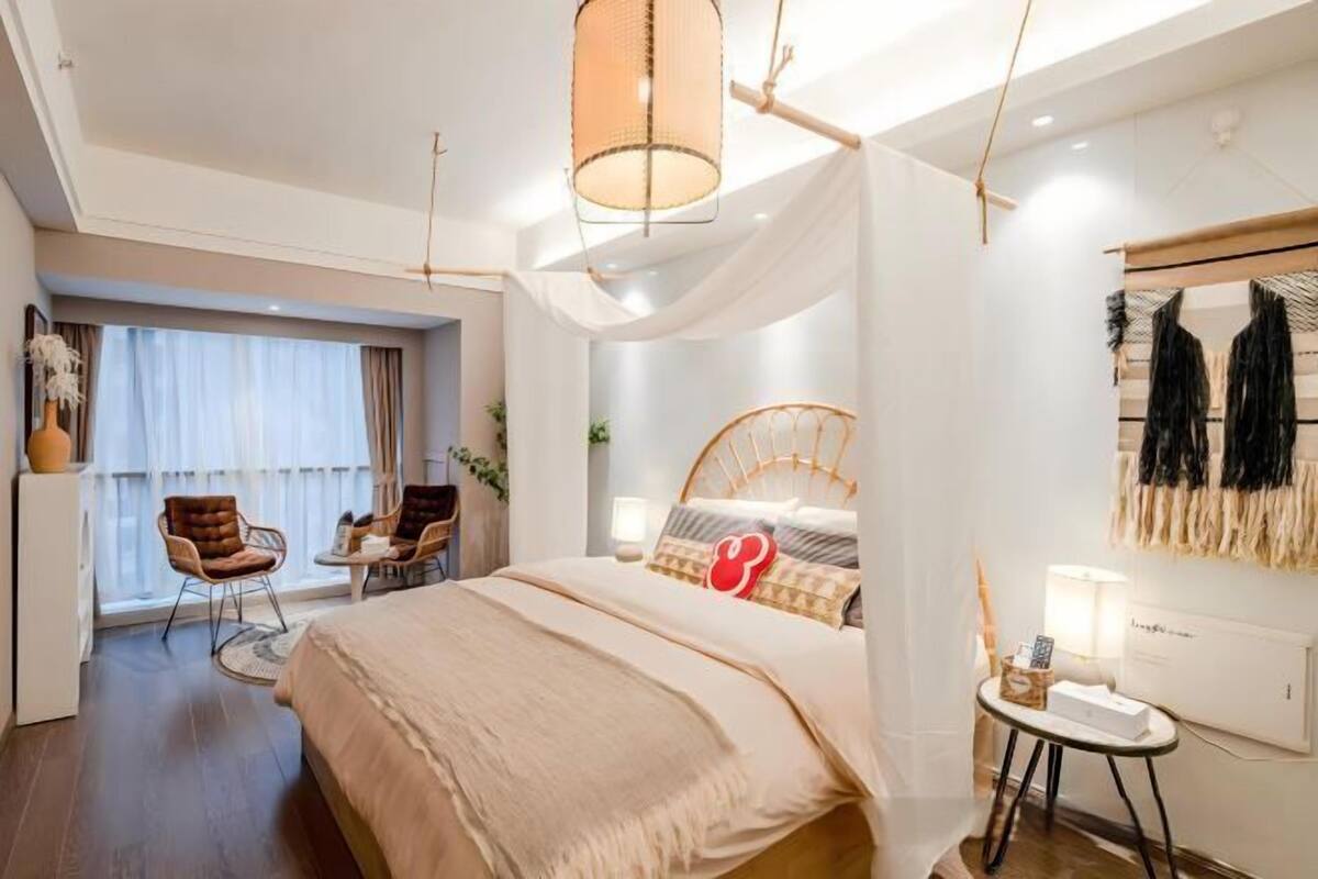 Un dormitorio moderno con una cama grande, una mesita de noche, una silla y una ventana con cortinas.