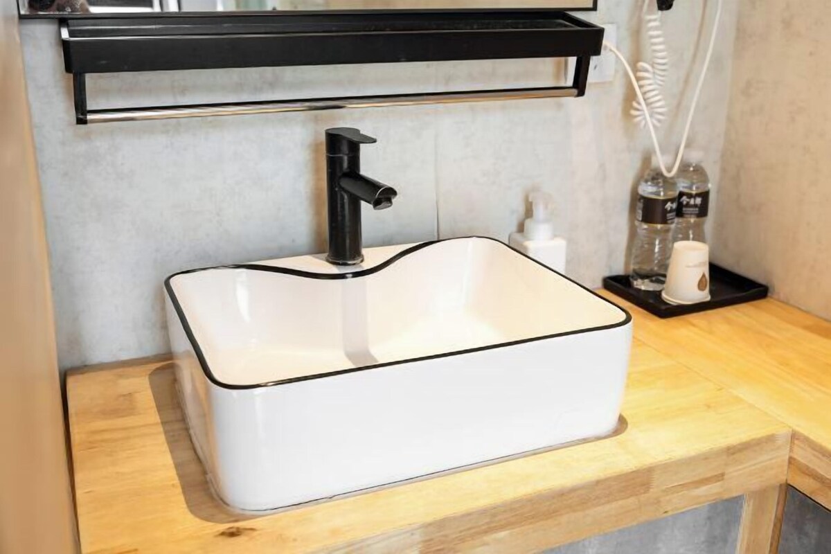 A bathroom with a white sink, black faucet, and a wooden countertop.