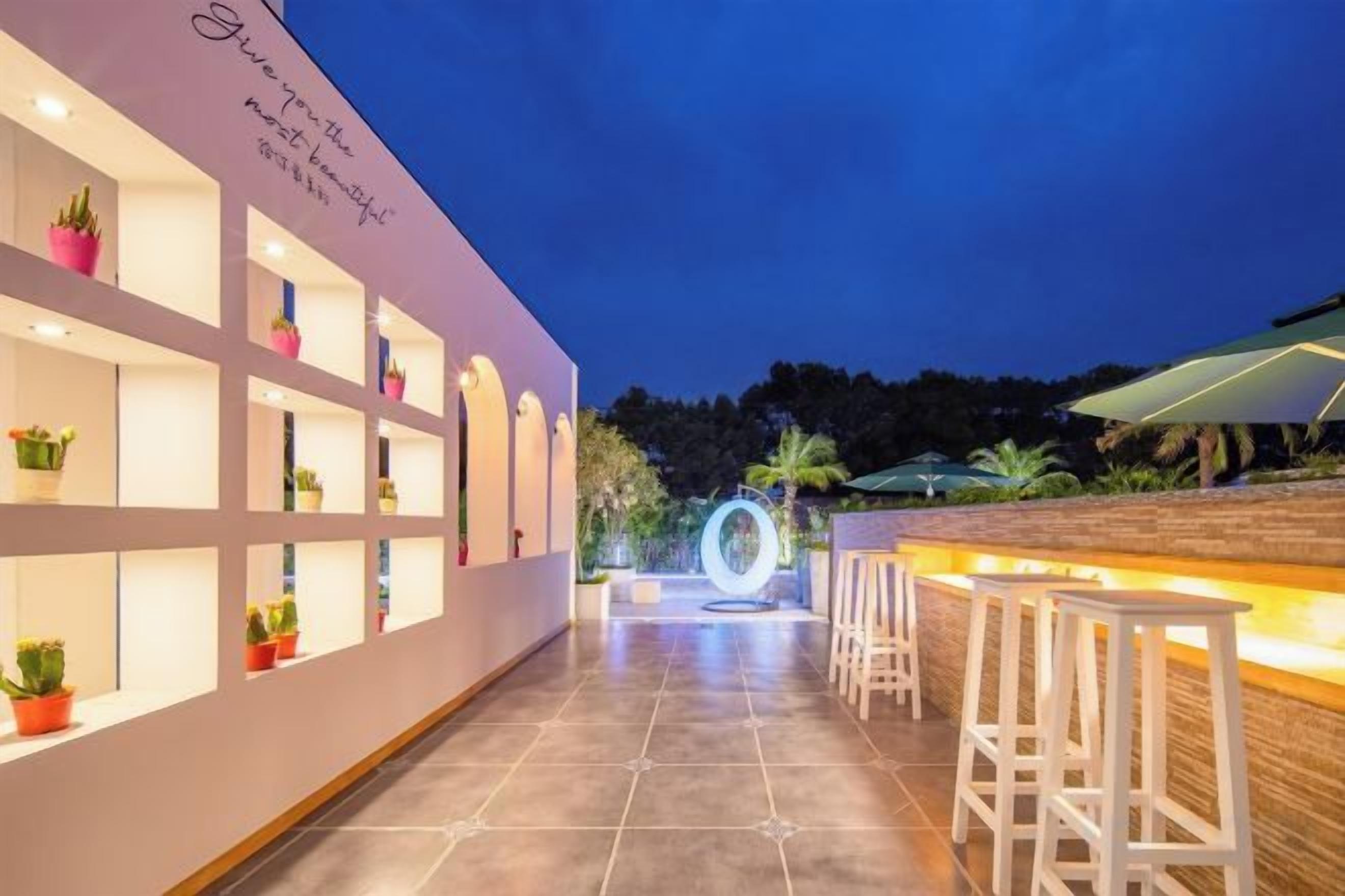 Área de bar moderna ao ar livre, com assentos e iluminação decorativa.
