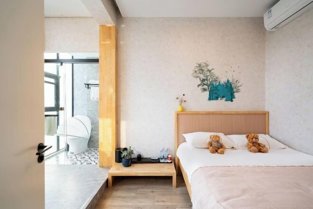 A modern hotel room with a bed, bedside table, and a wall-mounted artwork.