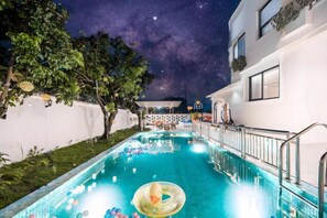 A swimming pool with a starry night sky, surrounded by a white building with a balcony. - Shanghai Qichi homestay (Shanghai)