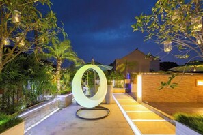 A pathway with a circular light fixture, surrounded by greenery and a building in the background. - Shanghai Qichi homestay (Shanghai)