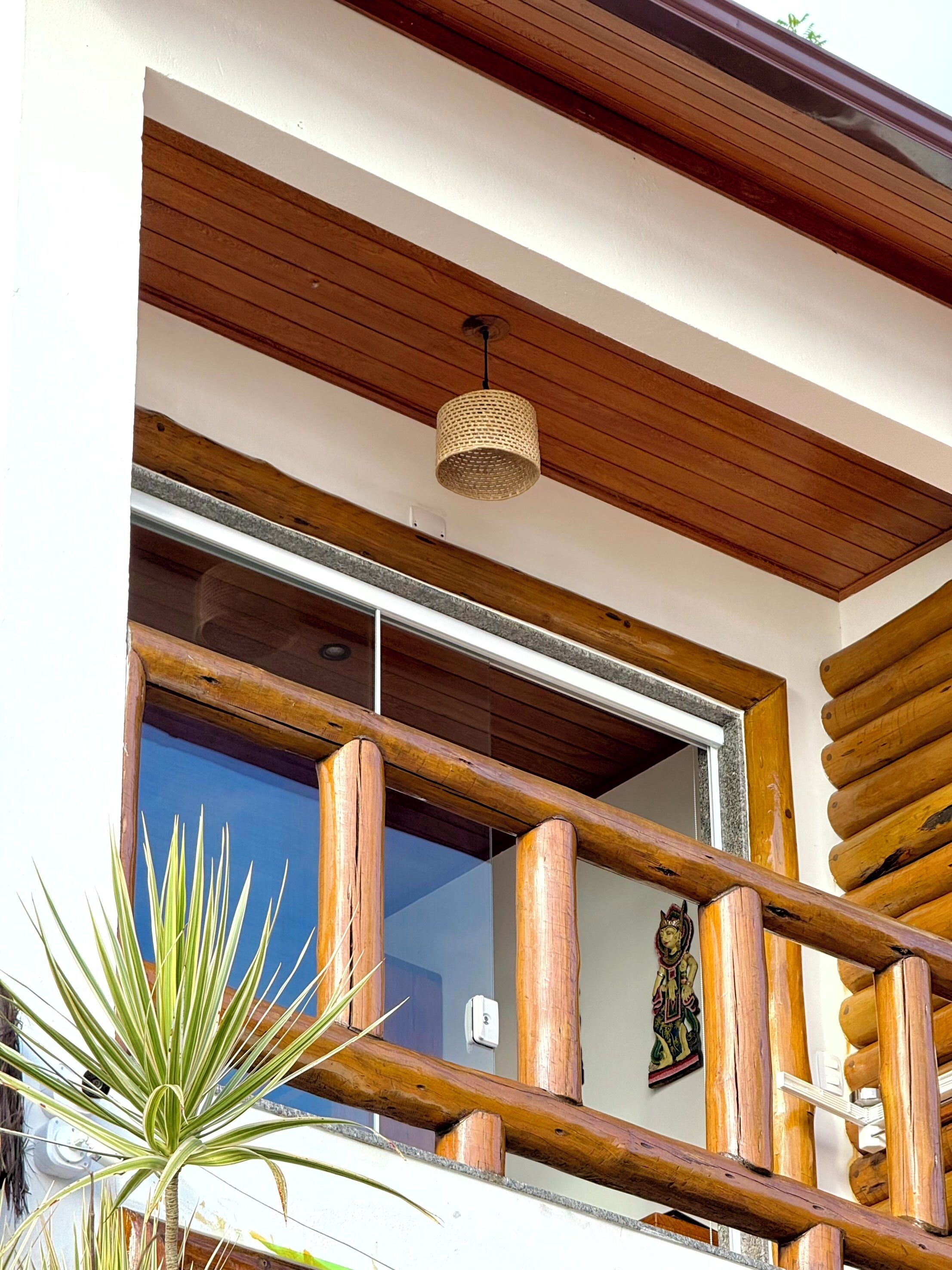 A wooden balcony with a woven light fixture, a decorative item, and a plant.