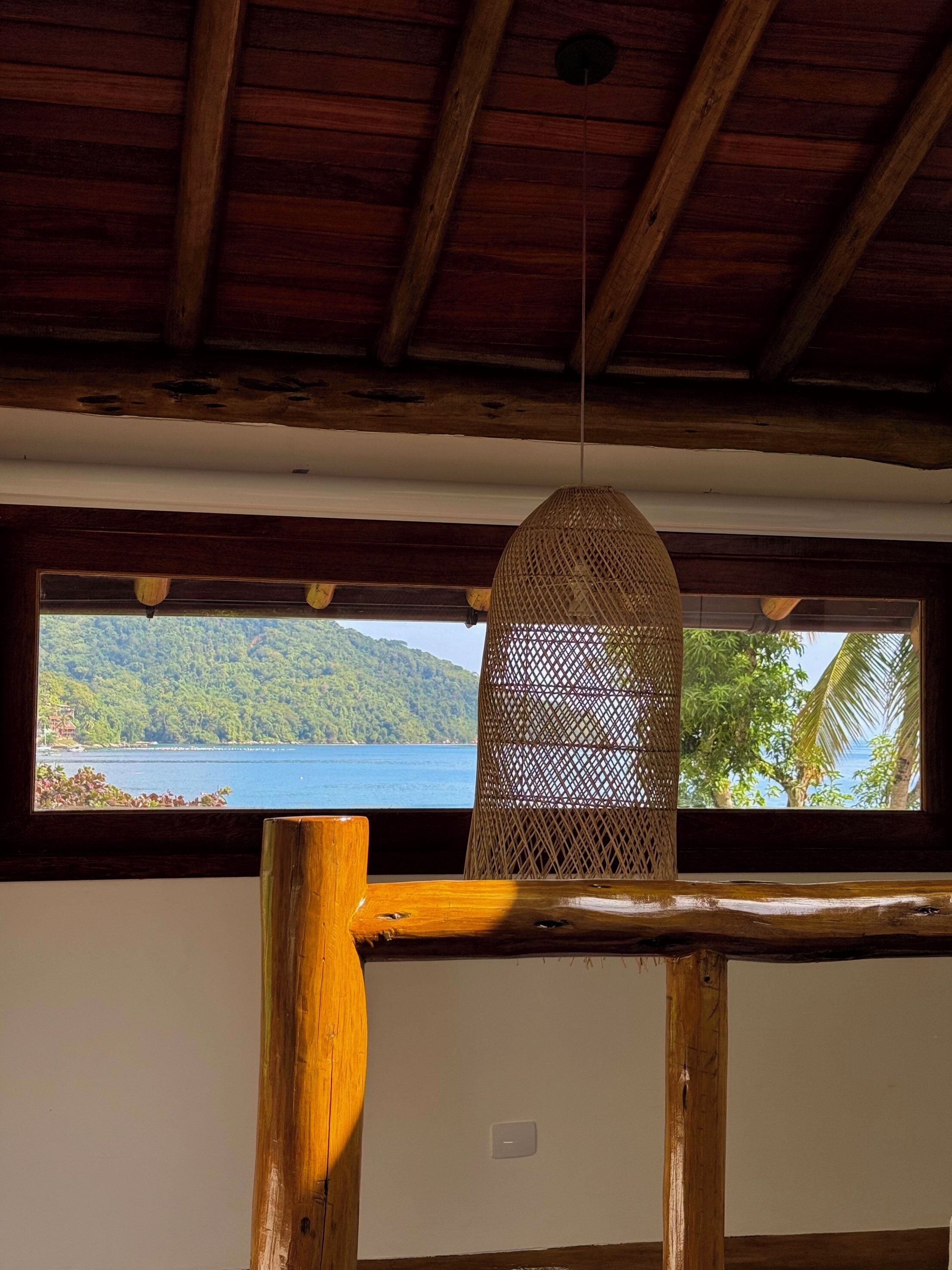 Techo de madera con una lámpara colgante de mimbre frente a una ventana.