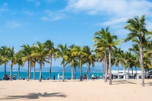 Ein Strand mit Palmen, wolkenlosem Himmel und ruhiger See.