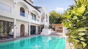 Ein modernes Haus mit Swimmingpool, Außenbereich und üppiger Bepflanzung.