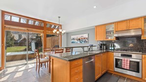 A modern kitchen with wooden cabinets, a built-in dishwasher, a stainless steel oven, and a large island with seating.