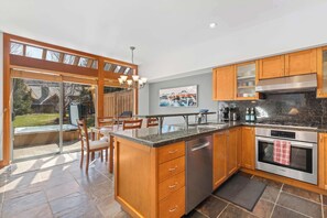 A modern kitchen with wooden cabinets, a built-in dishwasher, a stainless steel oven, and a large island with seating.