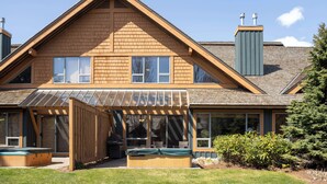 A two-story house with a covered patio, a hot tub, and a chimney.