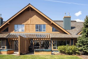 A two-story house with a covered patio, a hot tub, and a chimney. - Village North townhouse w/ hot tub (Whistler)