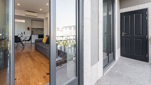 A modern apartment with a dining area, a living room with a sofa and cushions, and a balcony with a metal railing. - GuestReady - Rose Apartment (Porto)