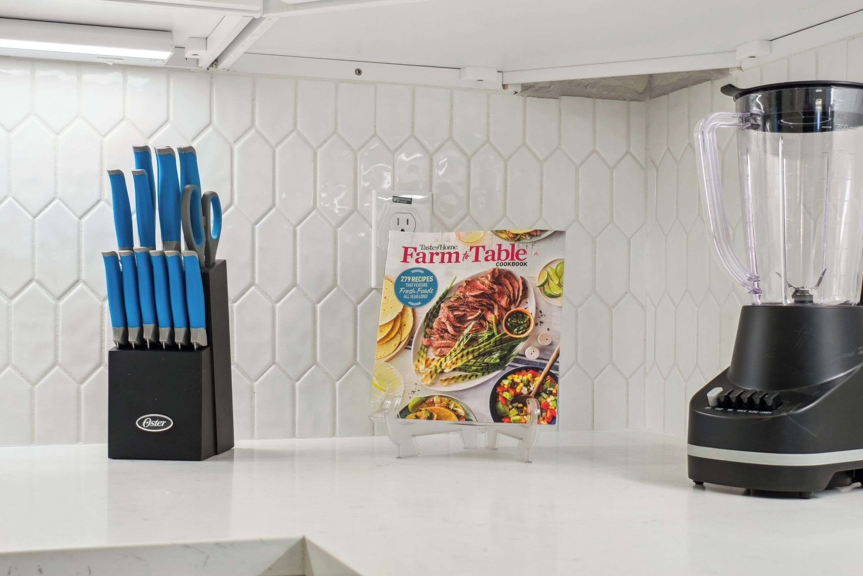 A kitchen counter with a knife block, a cookbook, and a blender.