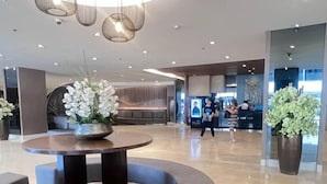 Eine moderne Lobby mit rundem Tisch, Sitzgelegenheiten und einer Rezeption.