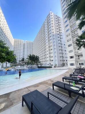 A swimming pool area with lounge chairs and a person swimming. - SHORE 1 RESIDENCES  (Pasay)