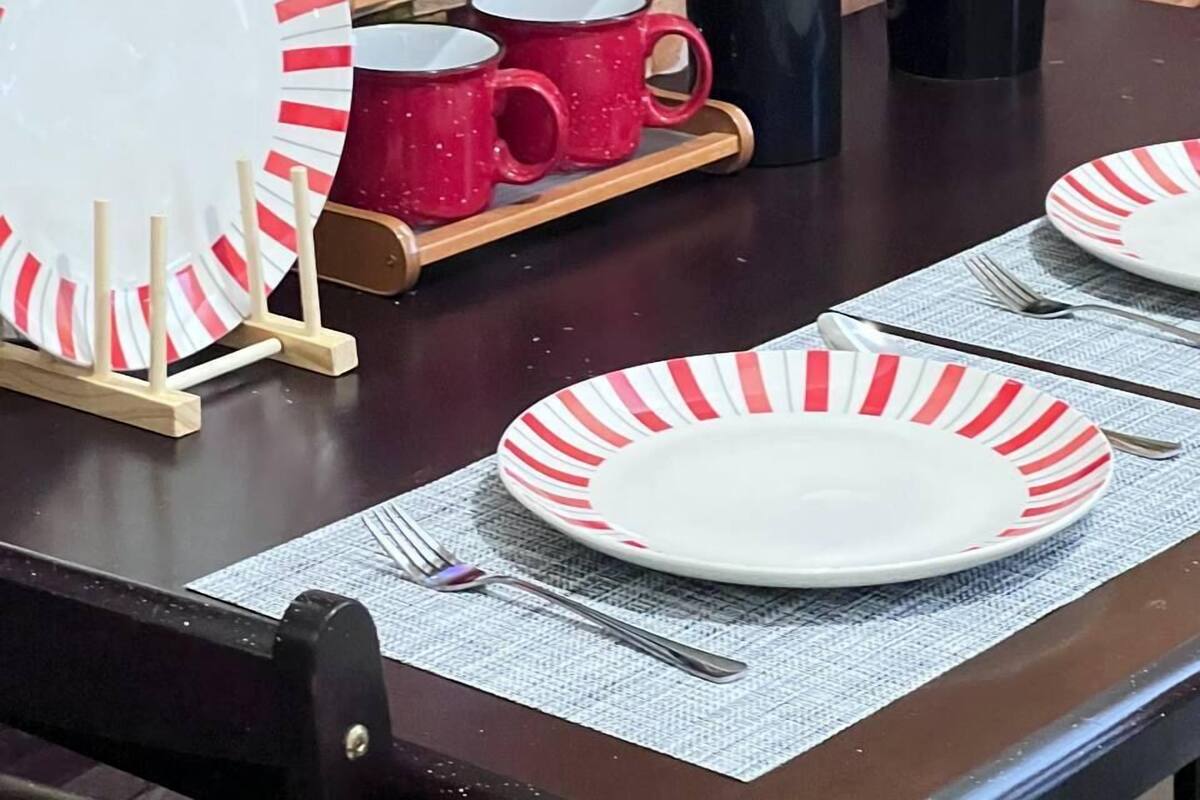 Une table à manger dressée avec des assiettes, des tasses et un vase de fleurs.