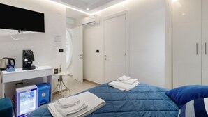 Une chambre d’hôtel moderne équipée d’un lit, d’un bureau avec une machine à café, d’une télévision et d’un appareil de climatisation.