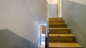 Un escalier muni d’une rampe, menant à une porte ouverte en haut.