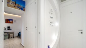 A hotel corridor with white doors, a coffee machine, a trash bin, and a painting on the wall. - Room 'Il Filo Di Arianna - Camera 2' with Wi-Fi and Air Conditioning (Bari)