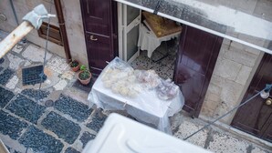 A balcony with a table covered in plastic, potted plants, and a door. - Room 'Il Filo Di Arianna - Camera 2' with Wi-Fi and Air Conditioning (Bari)