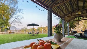 A covered patio with a table set for a meal, featuring a tray of oranges and a vase of flowers. - Xiang Zhu Zi Yuan (Guilin)
