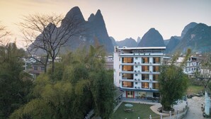 A multi-story hotel with a courtyard, surrounded by trees and mountains. - Xiang Zhu Zi Yuan (Guilin)