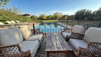 Un espace extérieur aménagé avec des meubles en osier et une table, donnant sur une piscine.