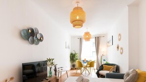 A modern hotel room with a bed, a TV, a dining area, and a living space.