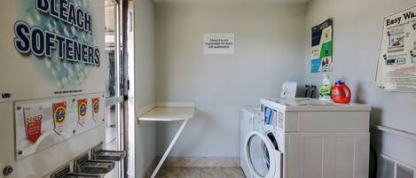 A laundry room with a washing machine, a coin-operated laundry machine, and detergent dispensers.