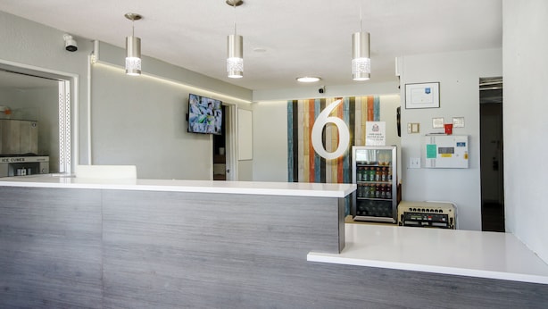 Un espace d’accueil moderne avec un comptoir de réception blanc, un grand chiffre « 6 » peint sur le mur et un distributeur automatique.