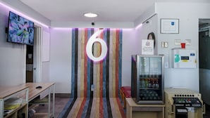 Une pièce avec un grand chiffre « 6 » peint sur le mur, un distributeur automatique et un appareil à eau fraîche.