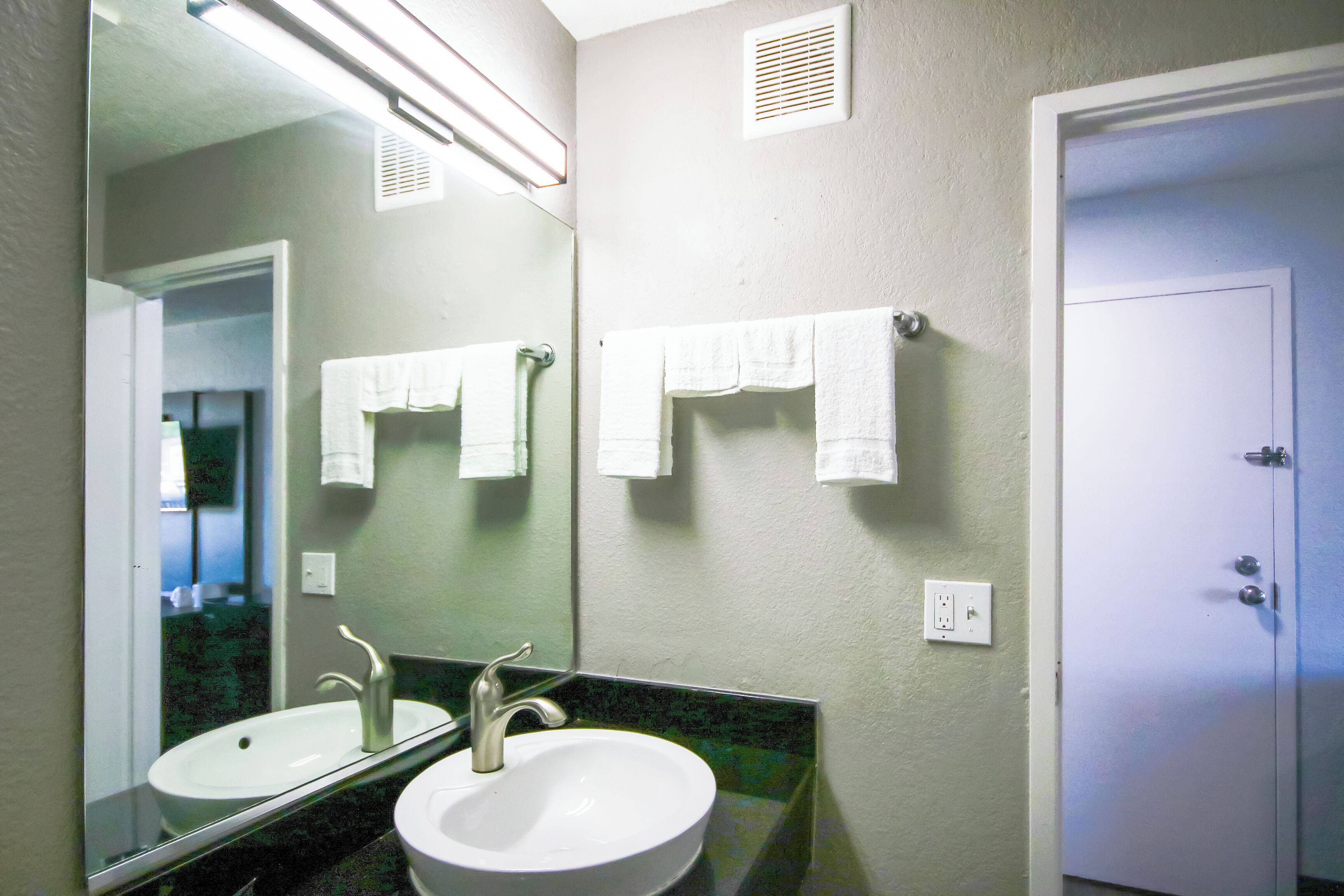A bathroom with a sink, mirror, and towel rack.