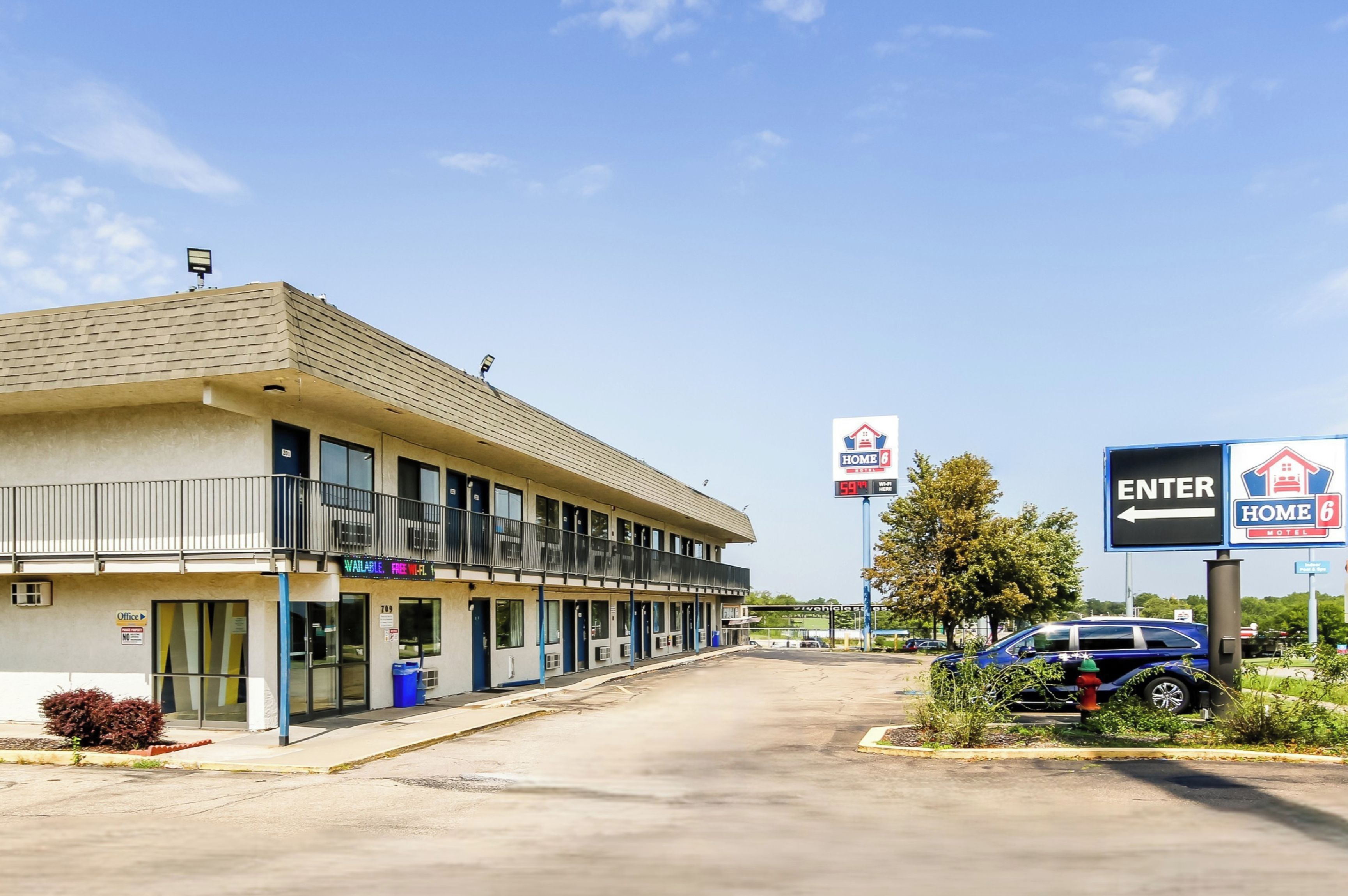 Un motel de planta baja, con zona de estacionamiento techada y un cartel con el nombre del motel.