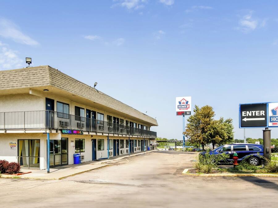 Un motel de planta baja, con zona de estacionamiento techada y un cartel con el nombre del motel.